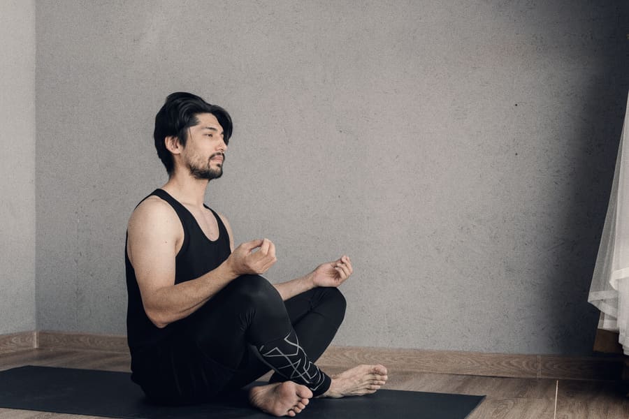 A seated breathing practice on a mat in early morning light, props set out on the floor