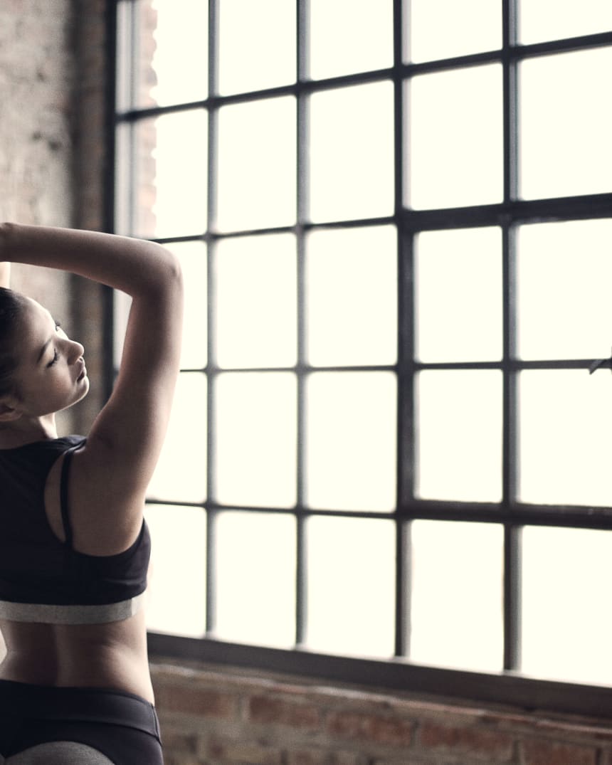 A practitioner stretching beside a tall studio window